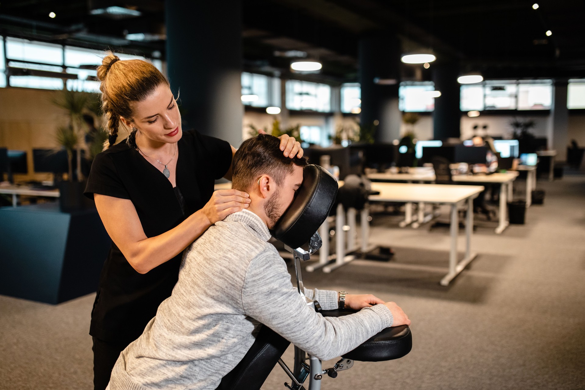 Jeune programmateur de businesscomputer stressé surmené appréciant le massage de cou dans la chaise de massage portable